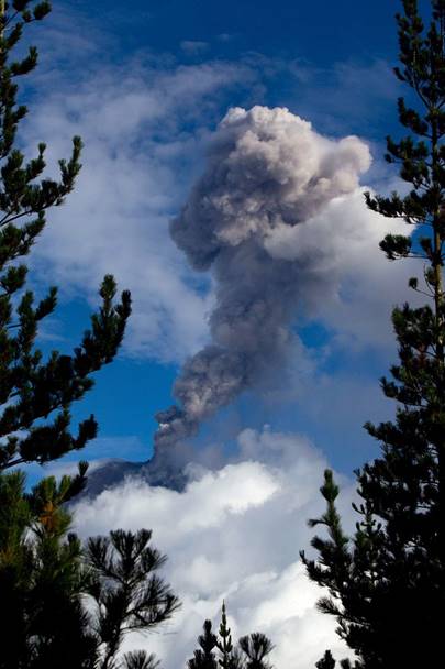 Photo of  Ecuadorian volcano Tungurahua spewing a column of smog and ashes as it is seen from the village of Pingue, Ecuador.