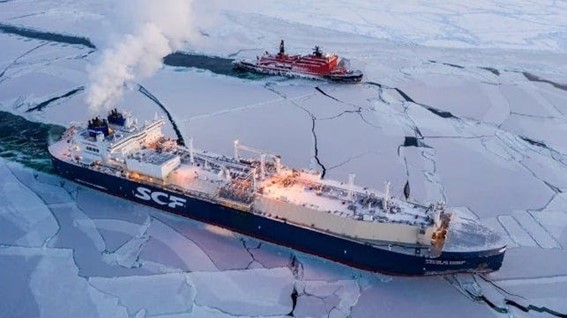 Large cargo ships navigating through broken sea ice in a frozen ocean environment.