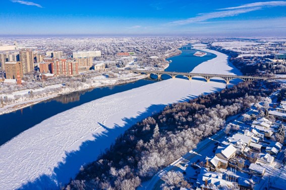 Frozen river and snow-covered city during extreme winter conditions.